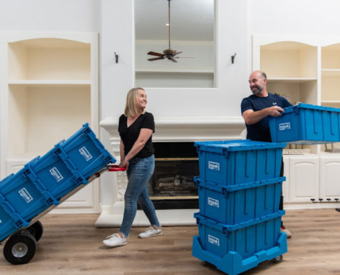 Couple smiling at each other while packing and moving items using EZPak's eco-friendly plastic bins