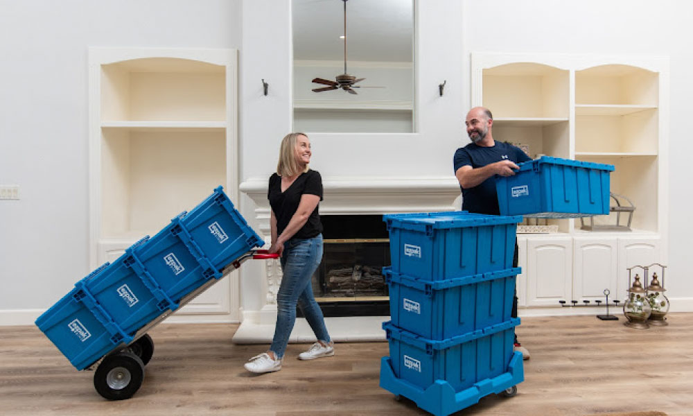 Couple smiling at each other while packing and moving items using EZPak's eco-friendly plastic bins