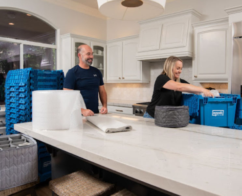 A couple packing kitchen items using EZPak's cleaner and more hygienic plastic bins