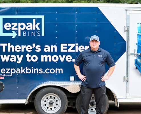 EZPak movers standing next to dolly carts and plastic bins ready to make your next Moving Services more convenient