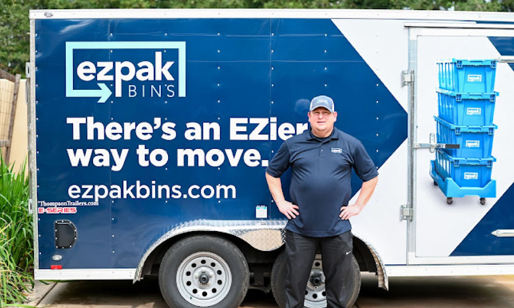 EZPak movers standing next to dolly carts and plastic bins ready to make your next move more convenient