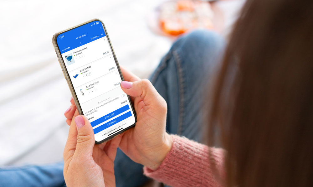 A woman holding smartphone and placing a rental order online for EZPack Bins