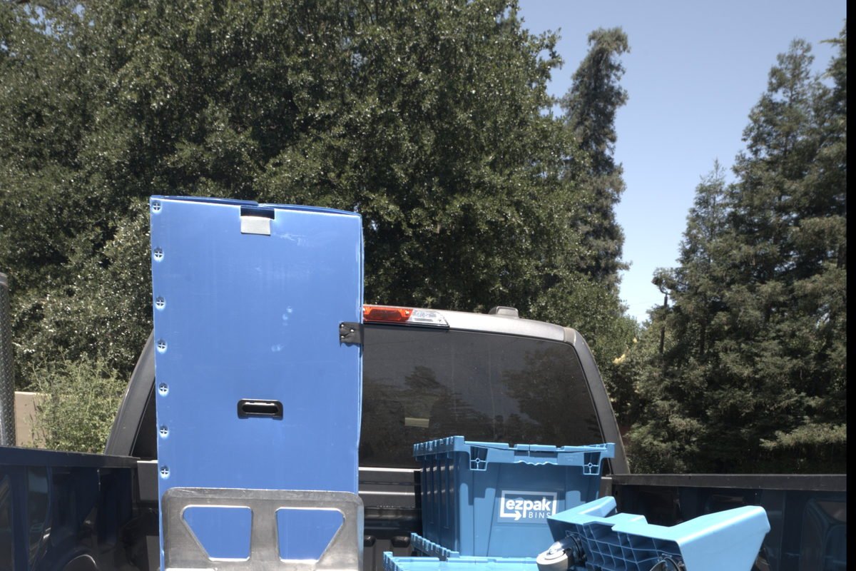 A hand truck and stacked blue EZPak Bins moving crates loaded in the bed of a pickup truck