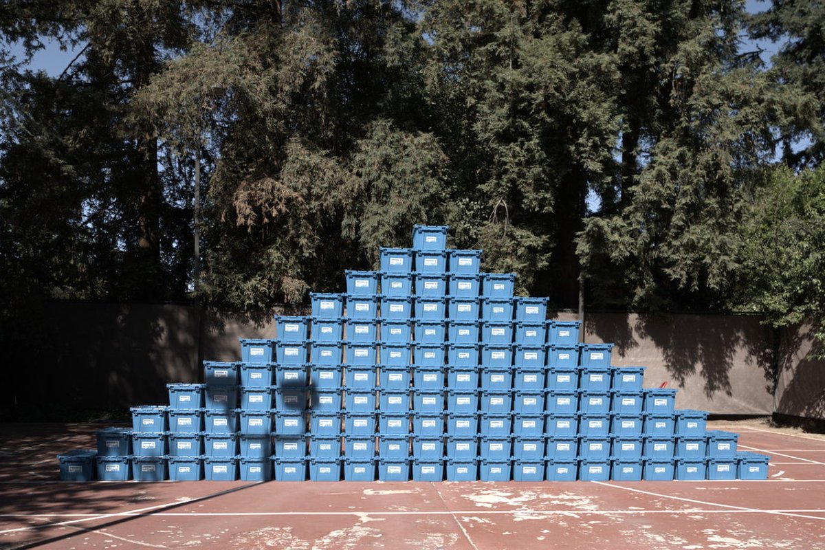 A large pyramid-shaped stack of blue EZPak Bins moving crates on an outdoor court