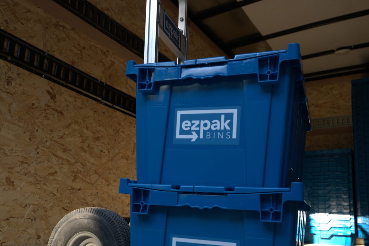 Two blue EZPak Bins moving crates stacked on a hand truck inside a cargo trailer