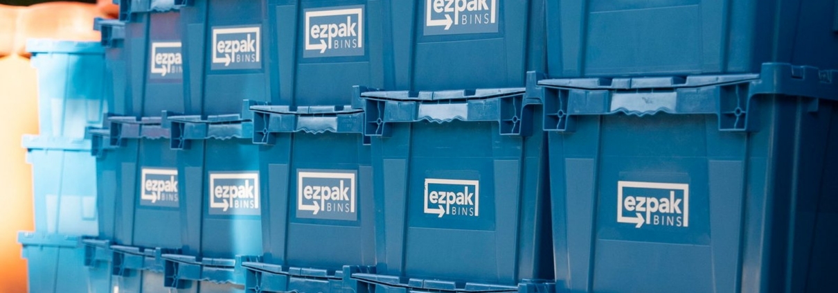 A wall of stacked blue EZPak Bins moving crates on wheeled dollies, branded and ready for moving in North Fresno