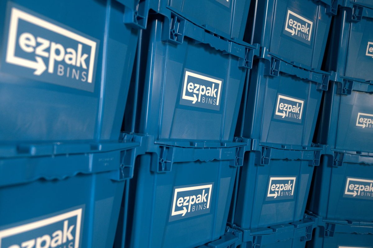 A close-up detail shot of many blue EZPak Bins moving bins stacked closely together, showing the branded logo repeated across each bin