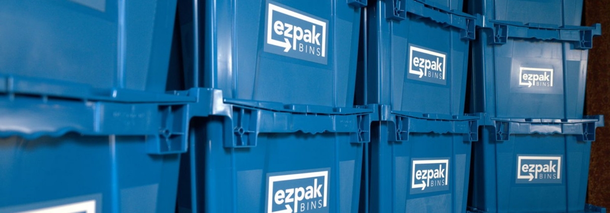 Many blue EZPak Bins moving bins stacked in tall columns inside a home hallway